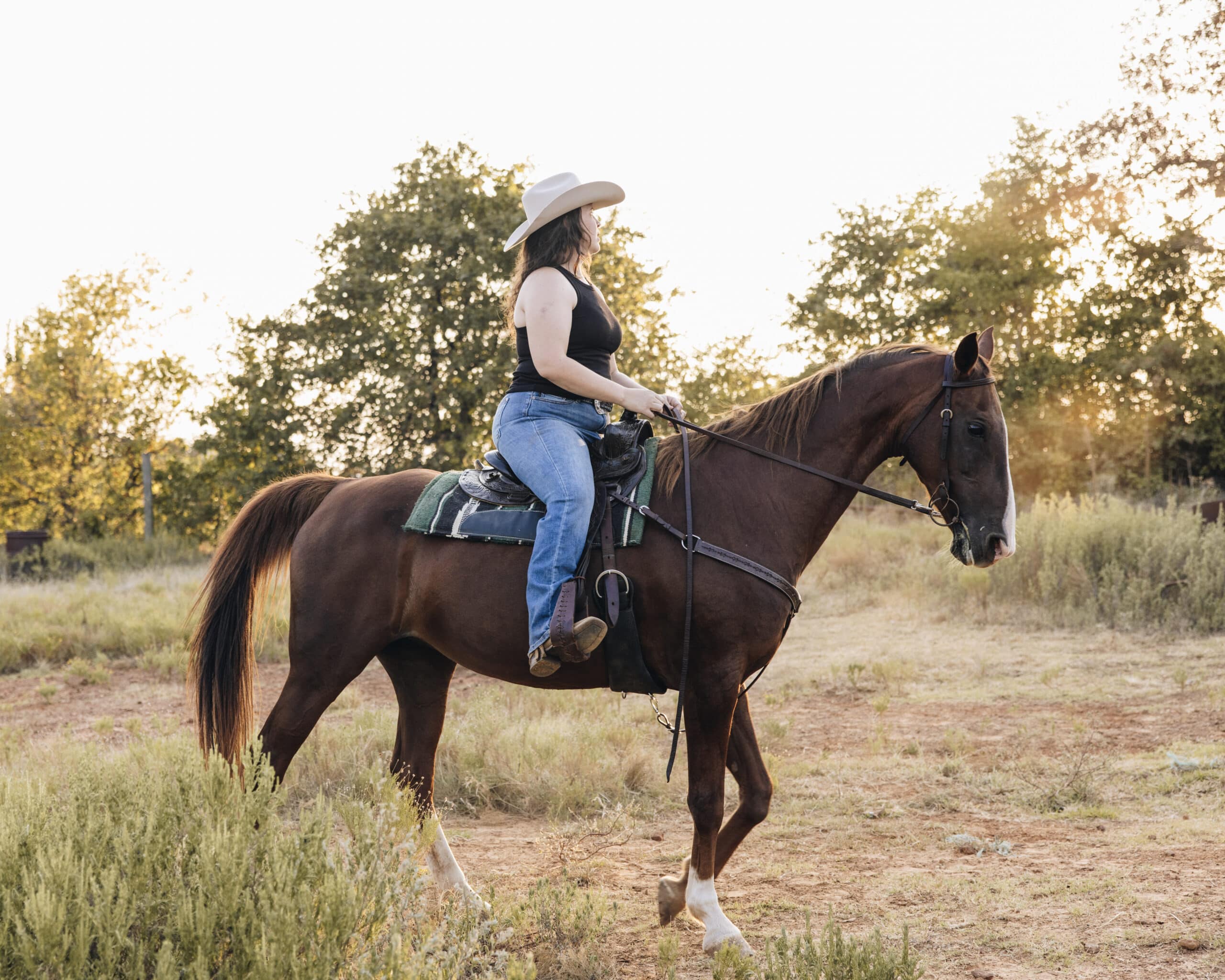 woman riding a dark haired horse wearing a twinstone hat cowboy hat