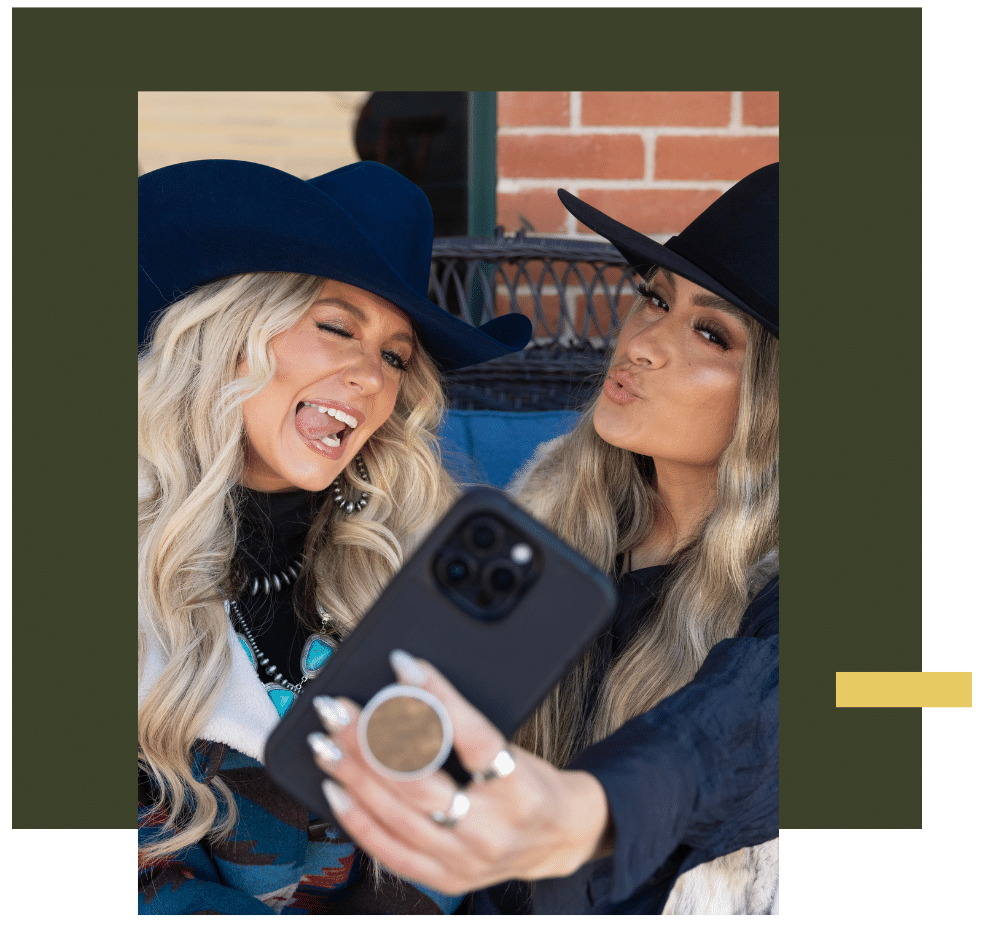 Two women wearing cowboy hats taking a playful selfie, representing Twinstone Hats with joy and personality.